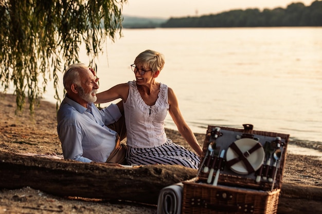 Heureux couple de personnes âgées ayant un pique-nique au bord de la rivière