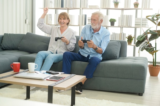 Heureux couple de personnes âgées caucasiennes jouant à des jeux à la maison