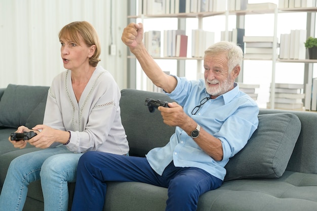 Heureux couple de personnes âgées caucasiennes jouant à des jeux à la maison