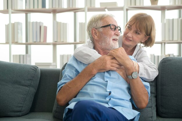 Heureux couple de personnes âgées caucasiennes relaxantes dans le salon à la maison