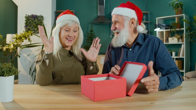 Photo heureux couple de personnes âgées en chapeaux de père noël célébrant noël en ligne