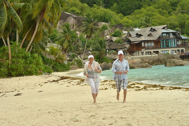 Heureux couple de personnes âgées courant sur une plage