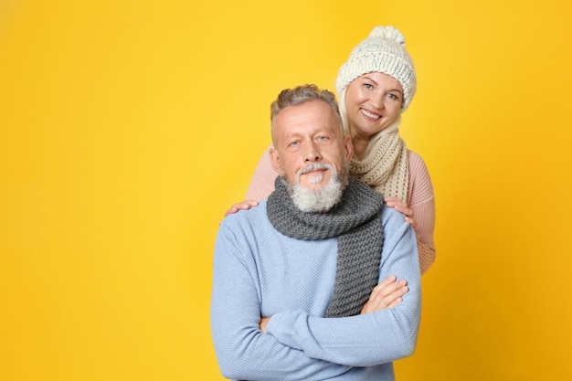 Heureux couple de personnes âgées dans des vêtements chauds sur fond de couleur