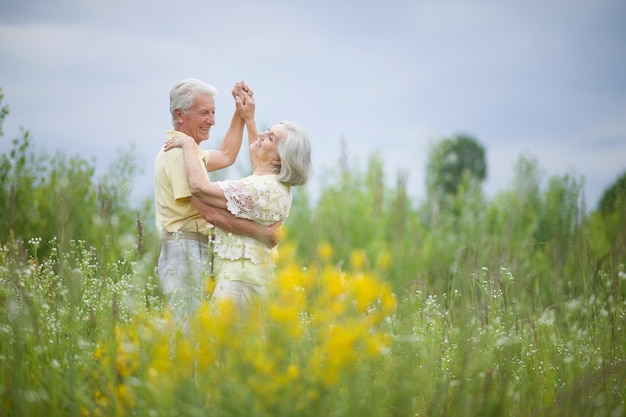 Heureux couple de personnes âgées dansant dans le parc d'été