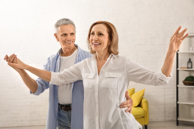 Heureux couple de personnes âgées dansant ensemble dans le salon