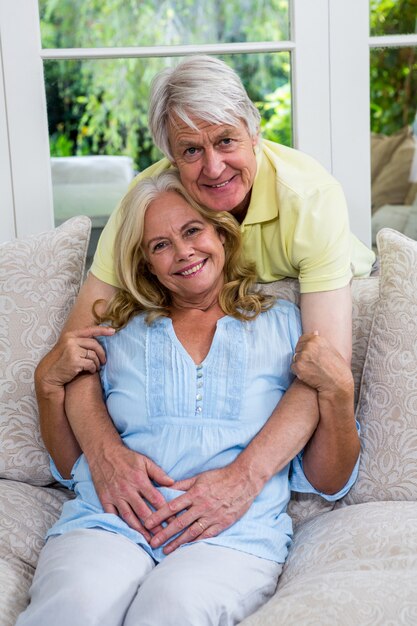 Heureux couple de personnes âgées embrassant dans le salon à la maison