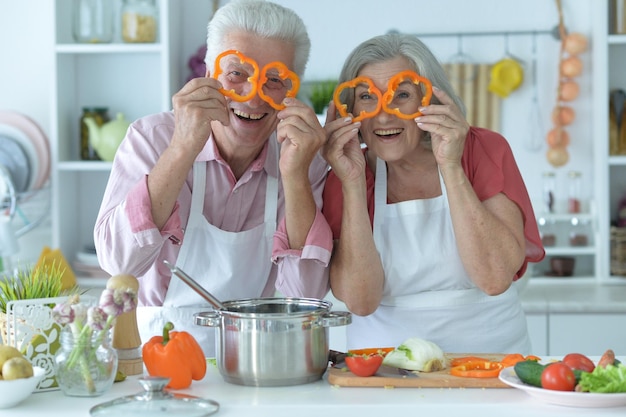 Heureux couple de personnes âgées faisant de la salade ensemble à la cuisine