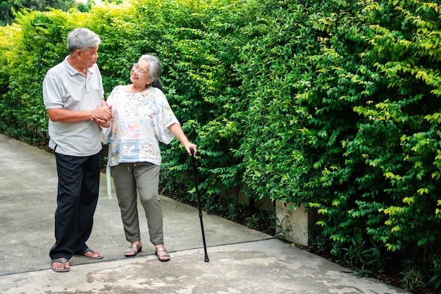 Heureux couple de personnes âgées marchant ensemble dans le jardin Personnes âgées utilisant un bâton de marche pour aider à marcher