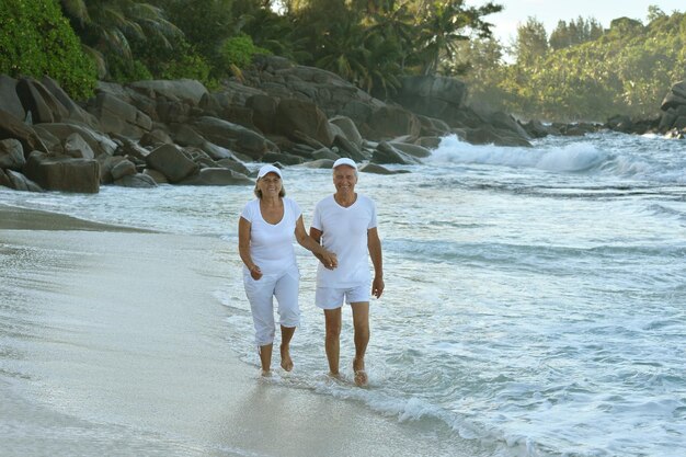 Heureux couple de personnes âgées marchant sur la plage tropicale