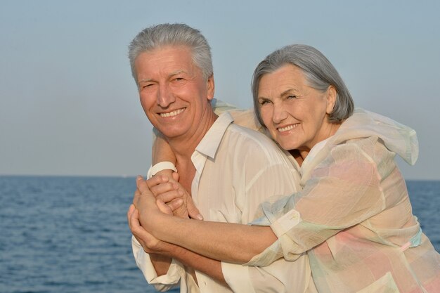 Heureux couple de personnes âgées mignon en mer au coucher du soleil