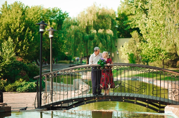 Heureux couple de personnes âgées se tenant debout sur le pont près de la rivière