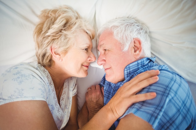 Heureux couple de personnes âgées se trouvant sur le lit