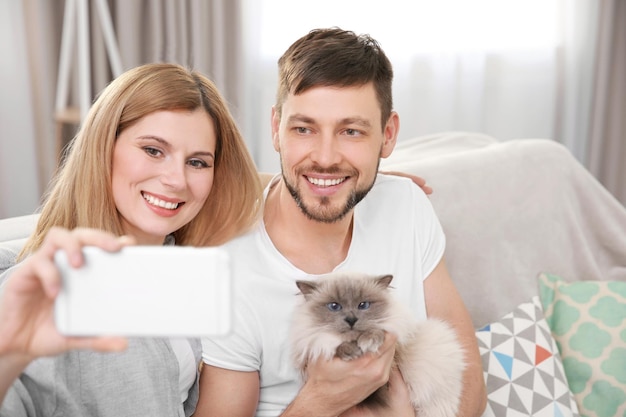 Heureux couple prenant une photo avec un chat à la maison