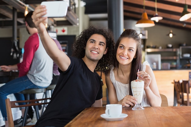 Heureux couple prenant selfie alors qu'il était assis au restaurant