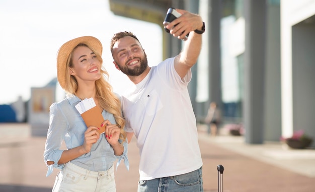 Heureux couple prenant selfie près de l'aéroport en attente d'embarquement