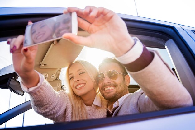 Heureux couple prenant un selfie en voiture