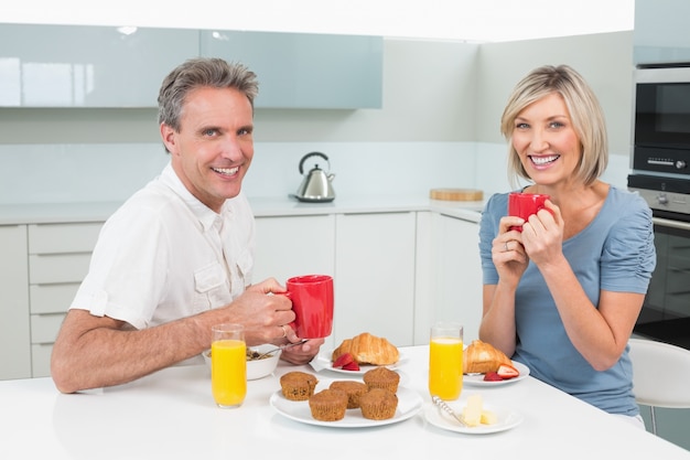 Heureux couple prenant son petit déjeuner dans la cuisine