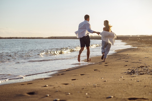 Heureux couple qui court le long de la plage main dans la main