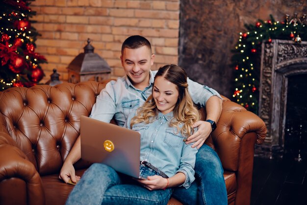 Heureux couple regardant moniteur d'ordinateur portable sur des décorations de Noël