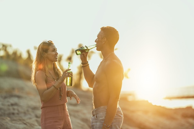 Heureux couple s'amusant et buvant de la bière à la plage.