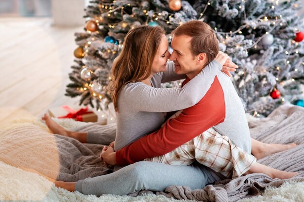 Heureux couple s'amusant près de l'arbre de Noël à la maison