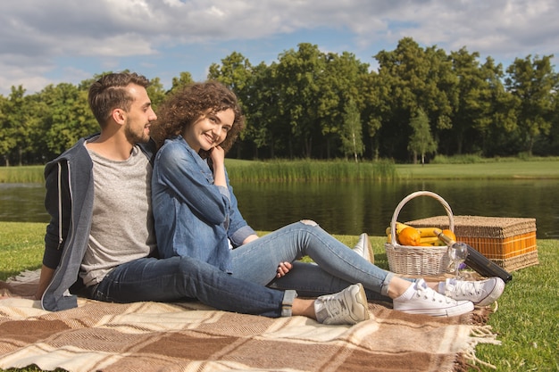 L'heureux couple s'assoit sur la couverture près de la rivière