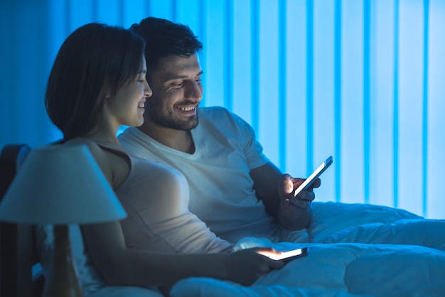 L'heureux couple s'assoit sur le lit et téléphone