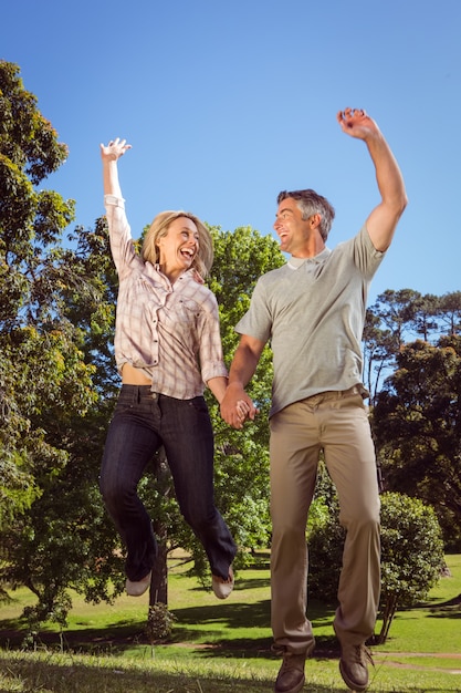 Heureux couple sautant dans le parc