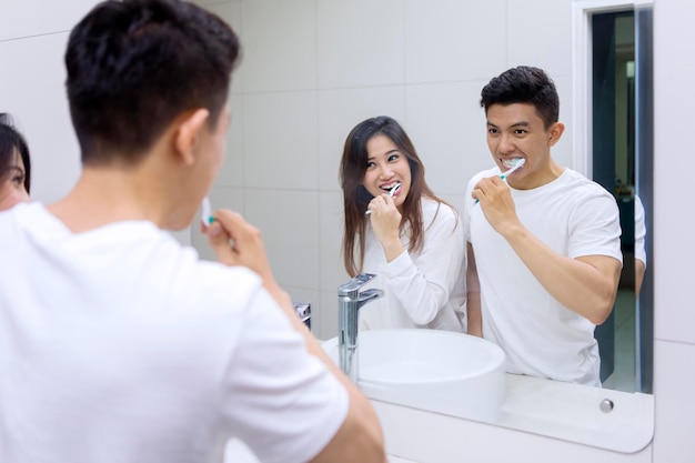 Heureux couple se nettoyant les dents ensemble dans la salle de bain