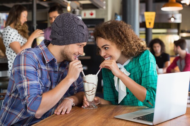 Heureux couple se regardant tout en ayant un milkshake