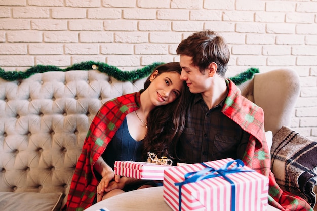 Heureux couple se reposant près des cadeaux de Noël.