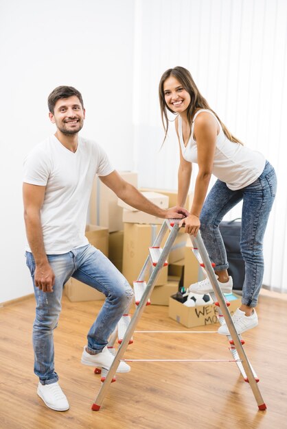 L'heureux couple se tient sur l'échelle sur le fond des boîtes en carton