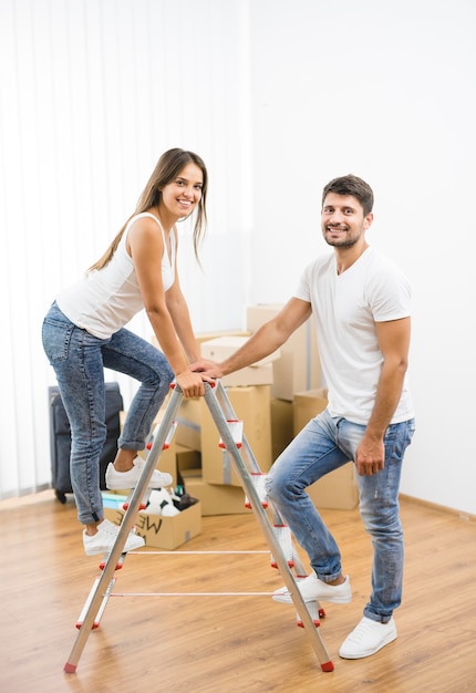 L'heureux couple se tient sur l'échelle sur le fond des boîtes en carton