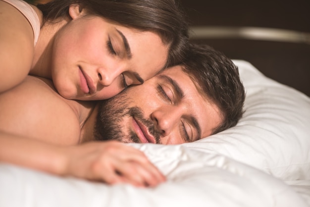 L'heureux couple se tient la main dans le lit