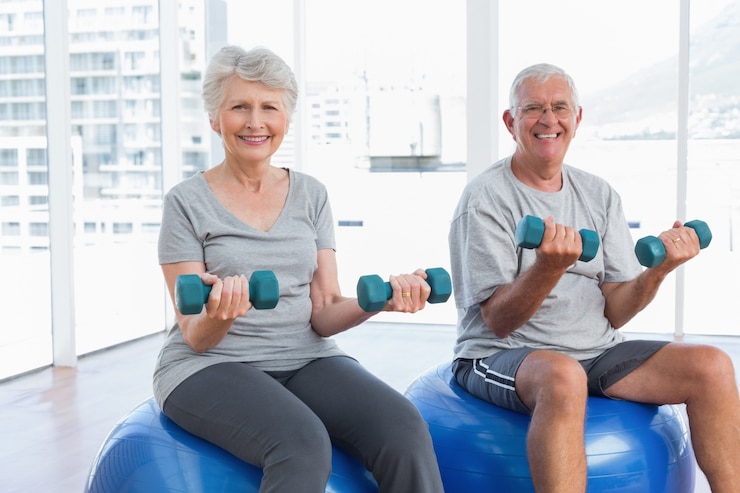 Photo heureux couple senior assis sur des ballons de remise en forme avec des haltères