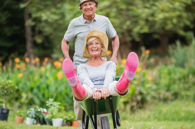 Heureux couple senior jouant avec une brouette