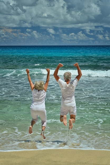 Heureux couple senior sautant en été au bord de la mer