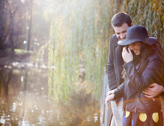 Heureux couple souriant marchant dans le parc d'automne près d'un lac