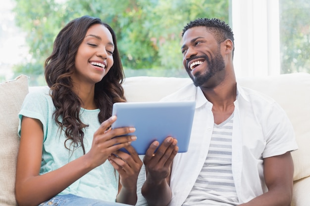 Heureux couple avec tablette ensemble sur le canapé