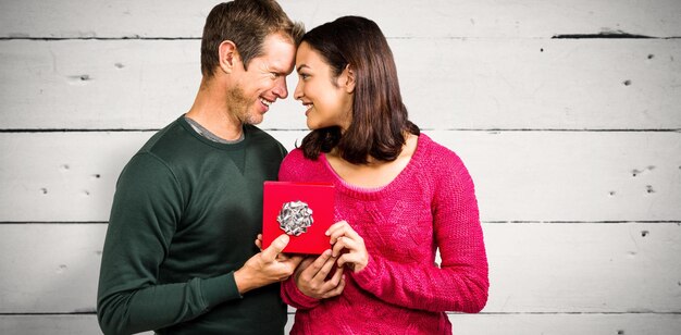 Photo heureux couple tenant une boîte-cadeau contre du bois blanc