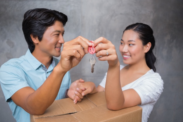 Heureux couple tenant la clé de la maison et s&#39;appuyant sur la boîte de déménagement