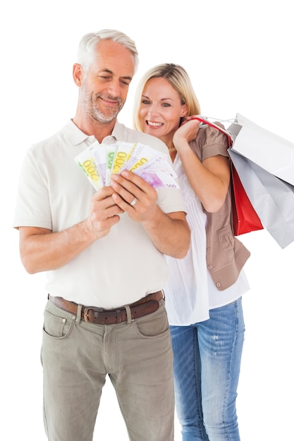 Heureux couple tenant des sacs à provisions et de l&#39;argent