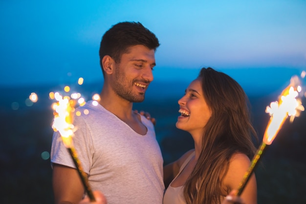 L'heureux couple tient des bâtons de feu d'artifice. le soir la nuit