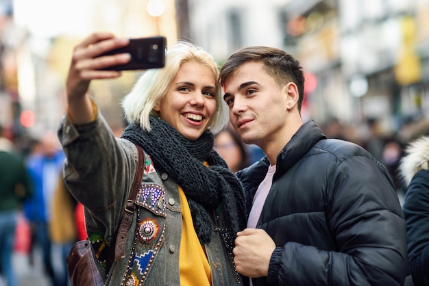 Heureux couple de touristes prenant selfie dans une rue bondée.