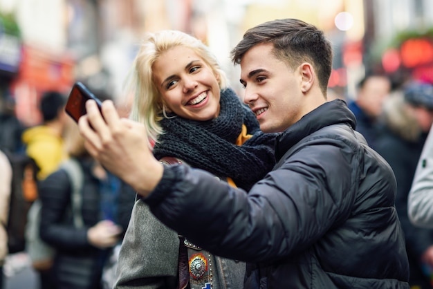 Heureux couple de touristes prenant selfie dans une rue bondée.