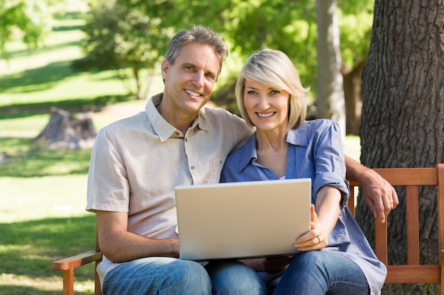 Heureux couple utilisant un ordinateur portable dans le parc