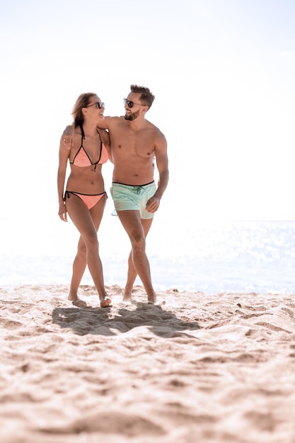 Heureux couple de vacances à la plage amusant marchant ensemble en riant s'amusant sur la destination de voyage