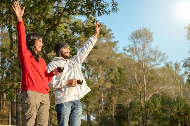 Heureux couple de voyageurs se reposant sur les montagnes au lever du soleil avec boire du café