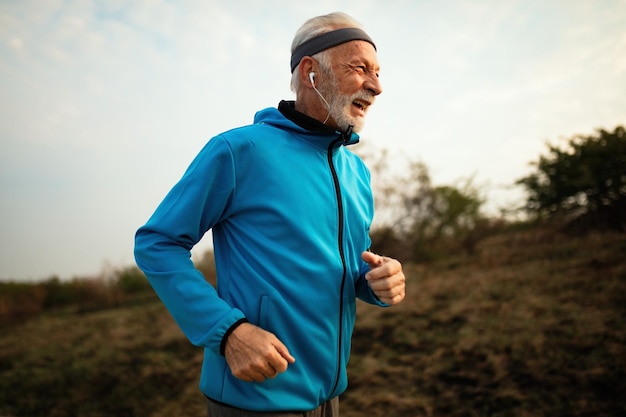 Heureux coureur senior profitant d'un mode de vie actif et faisant du jogging le matin dans la nature
