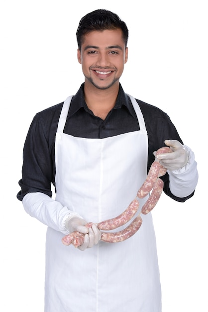 Heureux cuisinier tenant des saucisses et souriant.